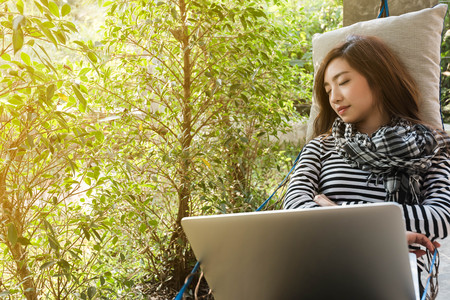 Young woman sleeping in hammock while use laptop, freelance life style conceptual, work anywhereの写真素材
