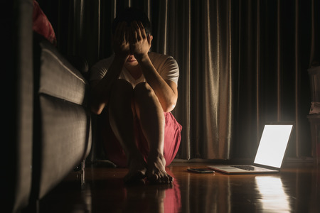 Man facing depression disorder sit on floor with laptop and smartphone beside, conceptual image showing effect from social media resulting in depression disorderの写真素材