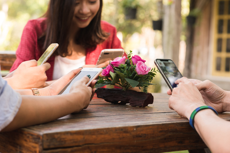 Hands of four teenagers use smartphone together in cafeの写真素材