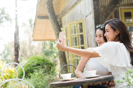 Life of generation Y teenagers hang out in coffee shop use smartphone play social media sharing digital content to each other with fun take selfie shotの写真素材