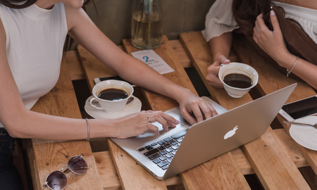 CHIANG MAI, THAILAND - FEBRUARY 19th, 2018: Two young women use Apple laptop, Mac book air in coffee shopのeditorial素材