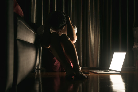 Man facing depression disorder sit on floor with laptop beside, conceptual image showing effect from social media resulting in depression disorderの写真素材