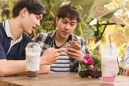 People adding friend play social media with smartphone together in coffee shopの写真素材