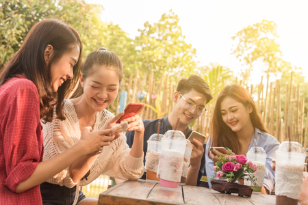 Group of teenager adding friend play social media with smartphone together in coffee shopの写真素材