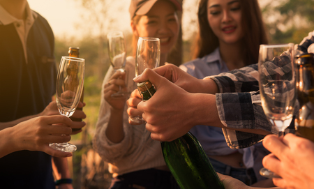 Hands of man in group of friends opening champange for celebrateの写真素材