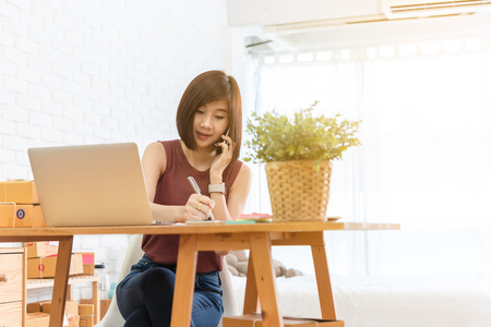 Woman small business owner, business start up conceptual, young entrepreneur work with laptop and smartphone take noteの写真素材
