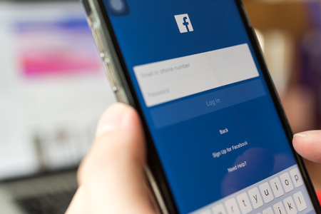 BANGKOK, THAILAND- 06 July 2018 : Hands of man use Facebook application log in screen on mobile phoneのeditorial素材