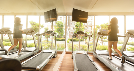 Woman run on running machine with on-ear headphone in gymの写真素材
