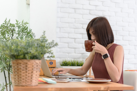 Woman small business owner, business start up conceptual, young entrepreneur check on laptop in the morning with coffee cupの写真素材