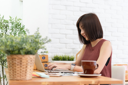 Woman small business owner, business start up conceptual, young entrepreneur check on laptop in the morning with coffee cupの写真素材