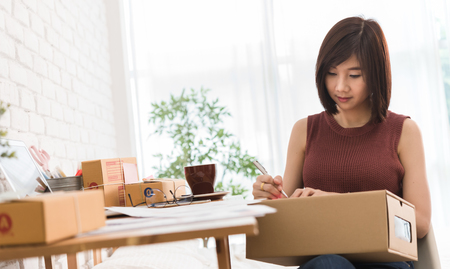 Woman small business owner, business start up conceptual, young entrepreneur preparing parcel for deliveryの写真素材