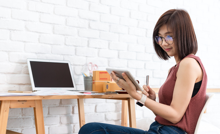 Woman small business owner, business start up conceptual, young entrepreneur work with laptop and tablet sell product on line shop in bedroomの写真素材