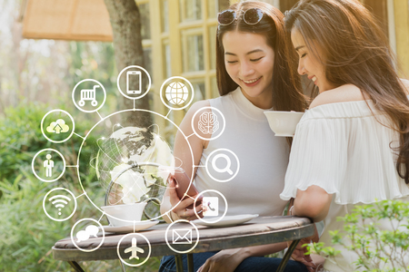 Two teenage women use smartphone with technology icon, internet of things conceptualの写真素材