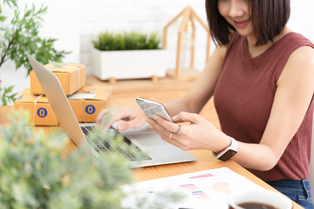Woman small business owner, business start up conceptual, young entrepreneur work with laptop and smartphone sell product on line shopの写真素材