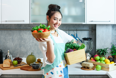 Woman in kitchen with various kind of vegetable and fruits that all are good for health and no meat, vegan lifestyleの写真素材