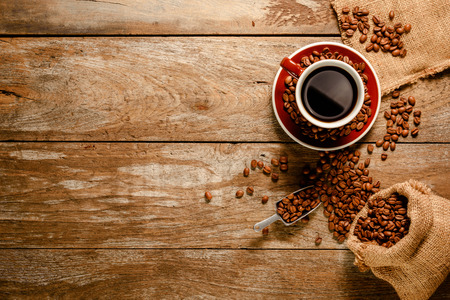 Top view ofa cup of black coffee with coffee bean bag, sugar, cinnamon and grounded coffee on wood background floorの写真素材