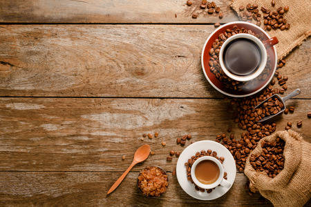 Top view of a cup of americano with coffee bean bag, sugar and cinnamon on wood background floorの写真素材