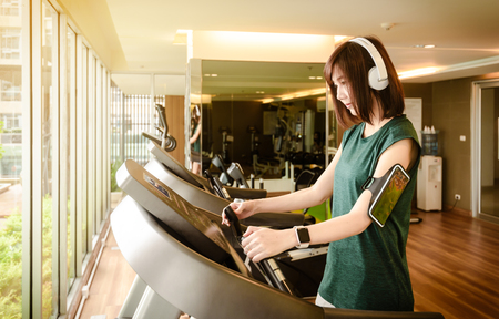 Woman start to run on running machine with on-ear headphone in gymの写真素材