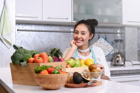 Woman in kitchen with various kind of vegetable and fruits that all are good for health and no meat, vegan lifestyleの写真素材