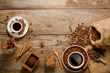 Top view of a cup of americano with coffee bean bag, sugar and cinnamon on wood background floorの写真素材