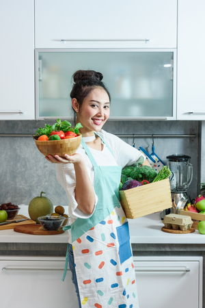 Woman in kitchen with various kind of vegetable and fruits that all are good for health and no meat, vegan lifestyleの写真素材