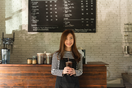 Woman coffee shop owner serving ice americano, young entrepreneurの写真素材