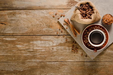 Top view of a cup of americano with coffee bean bag, sugar and cinnamon on wood background floorの写真素材