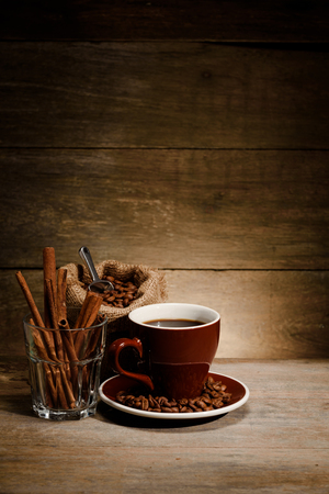 A Cup of black coffee with coffee bean bag and cinnamon on wooden floor, composition for book coverの写真素材
