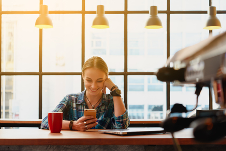 Young russian freelance use smartphone with laptop in coffee shopの写真素材