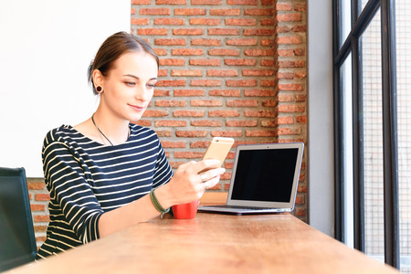 Woman freelance in coffee shop use smartphone and laptopの写真素材