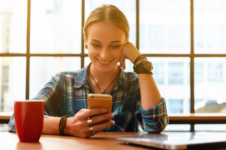 Young russian freelance use smartphone with laptop in coffee shopの写真素材