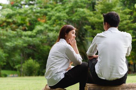 Man and woman in white shirt talk to each other in outdoors parkの写真素材
