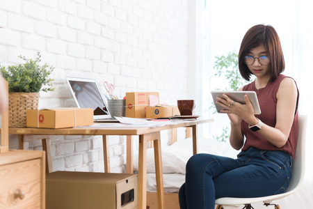 Woman small business owner, business start up conceptual, young entrepreneur work with laptop and tablet sell product on line shop in bedroomの写真素材