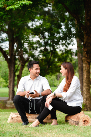 Man and woman in white shirt talk to each other in outdoors parkの写真素材
