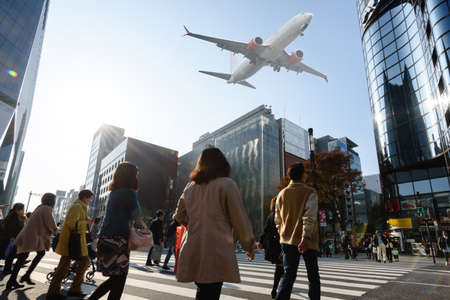 Scene of airplane over city with people cross roadのeditorial素材
