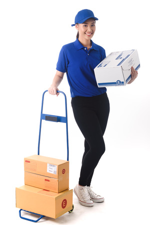 Beautiful young woman in blue uniform of delivery service, online shopping delivery conceptの写真素材
