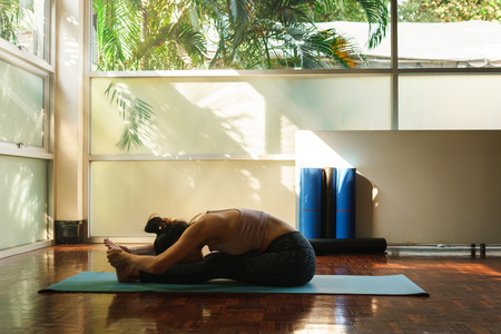 Young asian woman prepare for yoga training by streching back and legs with very flexible body reflection in windowの写真素材