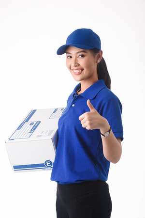 Beautiful young woman in blue uniform of delivery service, online shopping delivery conceptの写真素材