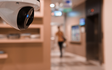 CCTV surveillance camera operating in front of elevator in buildingの写真素材
