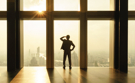 Two business man use smartphone by window on sky scrapperの写真素材