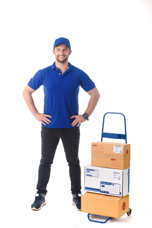 Delivery man in blue uniform of delivery service with trolley, online shopping delivery conceptの写真素材