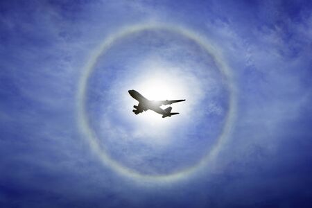 sun halo on blue sky with airplane fly pass by, fly high abstract conceptual imageの写真素材