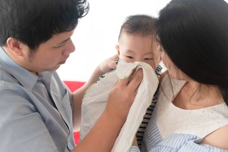 Father and mother take care of their baby have flu, sneeze and cough and have snot in nose