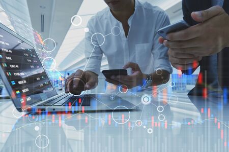 Two businessman work with laptop and diagram of stock market exchange technologyの写真素材