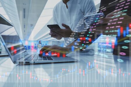 Two businessman work with laptop and diagram of stock market exchange technologyの写真素材