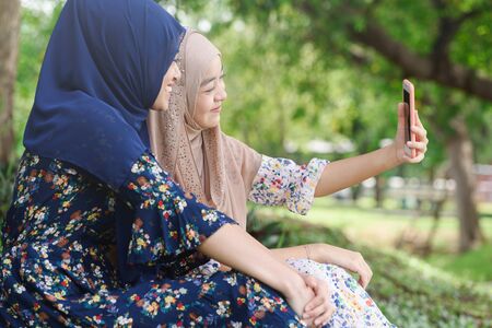 Two muslim woman use smartphone play social media together take selfie shotの写真素材