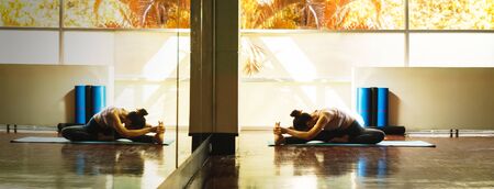 Young asian woman prepare for yoga training by stretching back and legs with very flexible body reflection in windowの写真素材