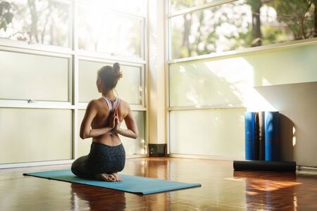 Skinny good looking asian woman practicing yoga alone in studio roomの写真素材