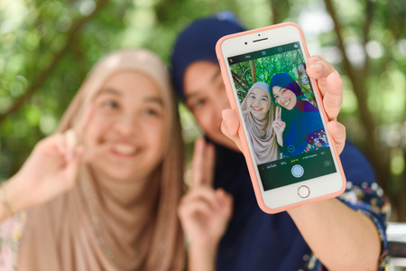 BANGKOK, THAILAND- 23th August 2019 : Hands of Islamic woman take selfie shot use her own smart...