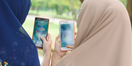 BANGKOK, THAILAND- 24th August 2019 : Hands of two Islamic woman use Iphone 7 plus with social media...